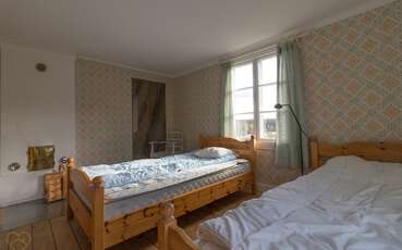 Schlafzimmer mit drei Einzelbetten und Kamin Ferienhaus Nedre Gården