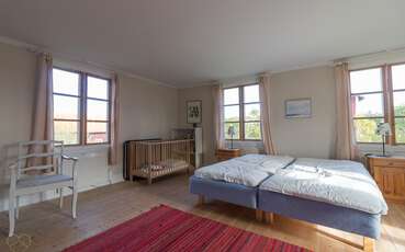 Schlafzimmer mit vier Einzelbetten und einem Babybett Ferienhaus Nedre Gården