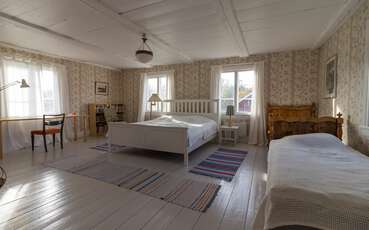 Schlafzimmer mit einem Doppeltbett und zwei Einzelbetten Ferienhaus Övre Gården
