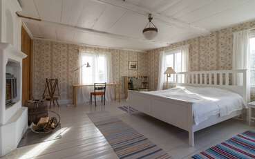 Schlafzimmer mit einem Doppelbett, zwei Einzelbetten und einem Kamin Ferienhaus Övre Gården
